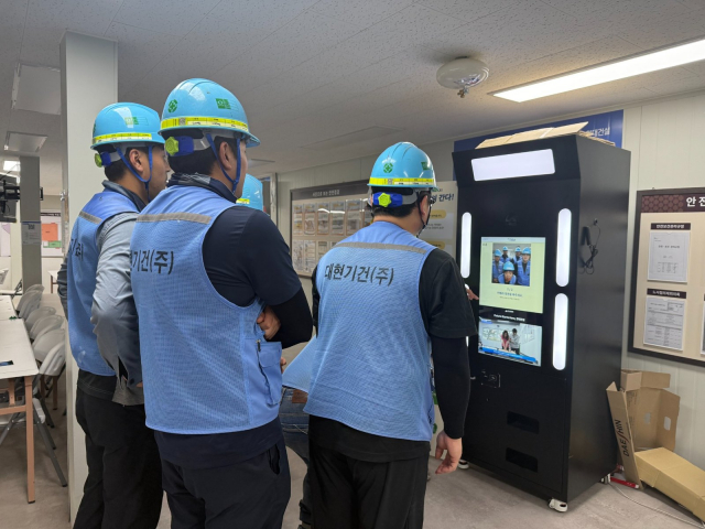 현대건설 공사 현장에서 근로자들이 안전 교육용 AI 안전네컷을 통해 작업 전 안전수칙을 점검하고 있다