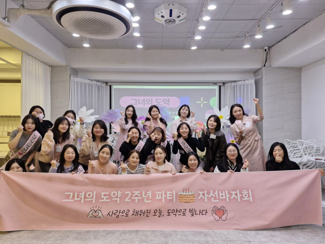 그녀의도약 2주년 행사에 참여한 멤버들이 현수막을 들고 기념 촬영한 모습. 참석자들이 함께 성장의 의미를 나누며 자선바자회를 마친 뒤, 감사와 축하의 순간을 기록했다
