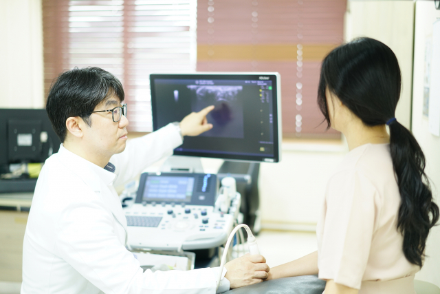 SRC재활병원 김은국 병원장이 진료실에서 초음파 검사를 진행하며 환자에게 검사 화면을 설명하고 있다