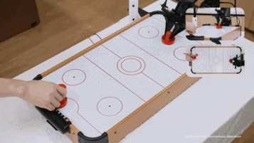 A robot powered by LingBot-VA 2.0 engages in a real-time tabletop air hockey match with a human